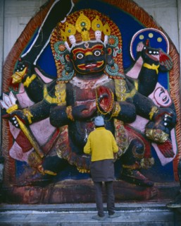 NEPAL, Kathmandu, "Man in front of temple carving of Black Bhairab in Durbar Square depicting Shiva