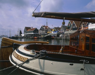 HOLLAND, North, Volendam, Harbour and buildings with many boats moored seen across the stern of a