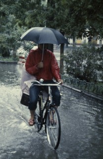 CLIMATE, Rain, Umbrella, Cyclist riding through flooded street holding umbrella with one hand