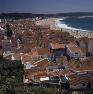 PORTUGAL, Estremadura, Nazara, View over main beach and town roof tops with mountains behind
