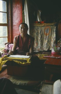 TIBET, Lhasa, Seated monk in room with prayer book
