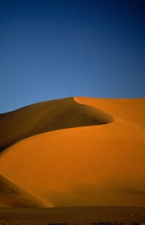 LIBYA , South West, Achan , Orange desert sand dune against a clear blue sky