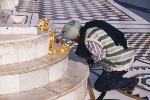 INDIA, Punjab, Amrtisar , Golden Temple.  Barefoot Sikh pilgrim kneeling at shrine to pray with