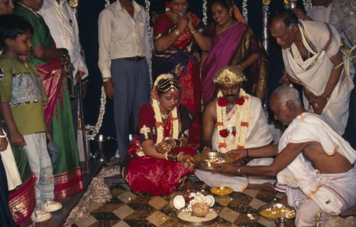 INDIA, Bangalore , Hindu Wedding, People standing around sitting couple wearing traditional wedding
