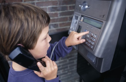 COMMUNICATIONS, Phones, Payphone, Young boy dialing on a payphone
