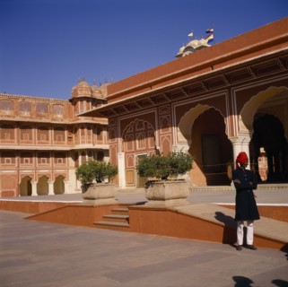 INDIA, Rajasthan , Jaipur , Palace exterior with man wearing red turban standing in grounds