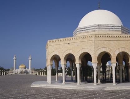 TUNISIA, Monastir, Bourguiba Mausoleum in distance beyond an arched portico with a white dome
