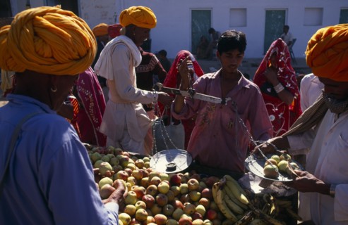 INDIA, Rajasthan , Pushkar , Vendor weighing apples for customer in fruit market.