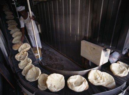 QATAR, Doha, Bakery.  Arab bread on a conveyor belt after coming out of the oven.