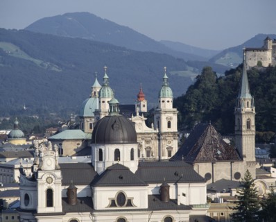 AUSTRIA, Salzburg Province, Salzburg, Town rooftops with domed spires a hilltop fortress and wooded