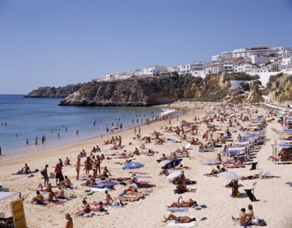 PORTUGAL, Algarve, Albufeira, View along the beach from above with sunbathers and the houselined