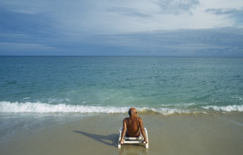 THAILAND, Surat Thani, Koh Samui, Lamai beach with lone male tourist sitting on a sunbed on the