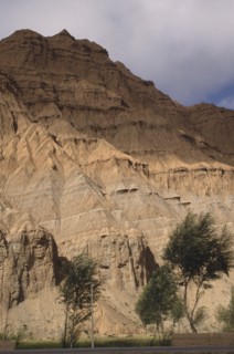 CHINA, Qinghai , Eroded rocky cliffs above wheat field in a high altitude remote valley near the