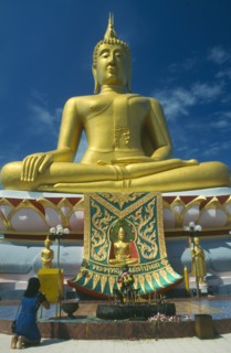 THAILAND, Surat Thani, Koh Samui , Woman praying before statue of Buddha at the Big Buddha Temple