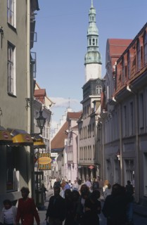 ESTONIA, Tallinn, Shops and a Church with a tower in a street in the Old Town busy with pedestrians