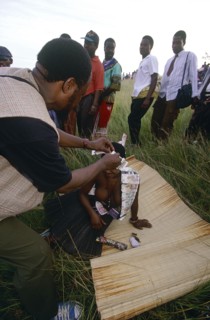 SOUTH AFRICA, KwaZulu Natal , Melmoth, Zulu man pinning money to a girl's head whilst she sits on a