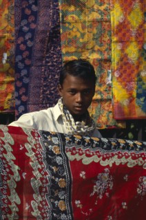 BANGLADESH,  , Dhaka, Fabric trader holding up printed cotton.