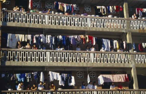 10122697 CHINA Yunan Province Jinghong Laundry hanging on apartment balconies in the Xishuangbana area with residents looking down on street.