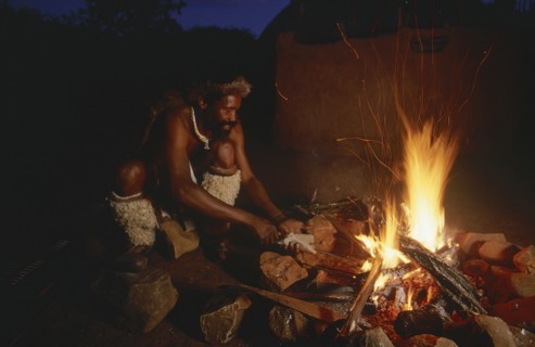 SOUTH AFRICA, Kwa Zulu Natal , Eshowe, Zulu man making a spear over an open fire at night outside