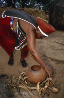 SOUTH AFRICA, Kwa Zulu Natal , Eshowe, Zulu woman preparing fire for firing pot.