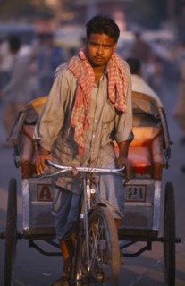 INDIA, Uttar Pradesh, Delhi, Rickshaw driver cycling on the road in the early morning