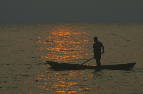 TANZANIA, Lake Tanganyika, Mokoro canoe raft paddler on water at sunset