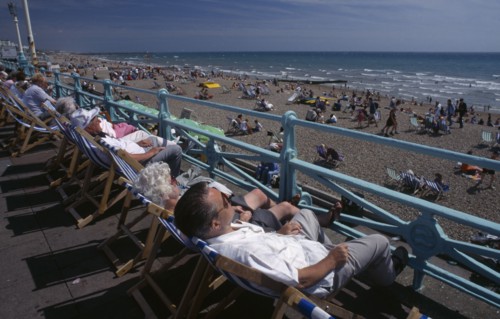 ENGLAND, East Sussex, Brighton , View over people in deckchairs lining the promenade toward the