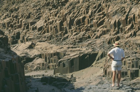 NAMIBIA, Landscape, Desert, Organ Pipes.Outcrop of volcanic basalt rock in desert . Man standing