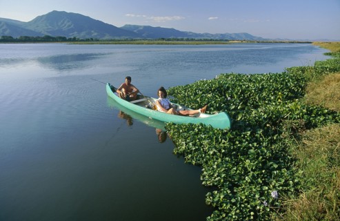 ZIMBABWE, Mashonaland, Mana Pools National Park, Couple fishing for bream in a canoe on the Zambezi