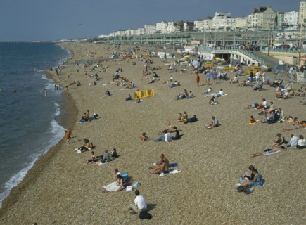 ENGLAND, East Sussex, Brighton, People sitting on the beach in summertime