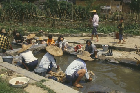 CHINA, Guangxi , Rongshui, Women and children washing clothes in village stream.