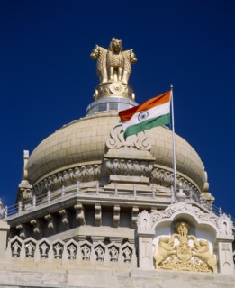 INDIA, Karnataka, Bangalore, "Vidhana Soudha building.  Exterior detail of roof dome, crest, flag