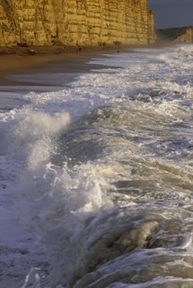 ENGLAND, Dorset, West Bay, Chesil Bank with waves breaking on the pebble beach below the cliffs