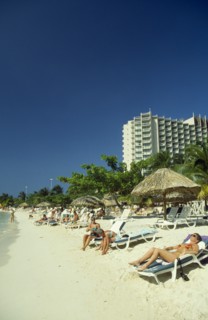 WEST INDIES, Jamaica, Ocho Rios, Sunbathers on the beach with hotel behind