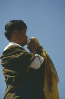 CHINA, Qinghai, Tongren, Tibetan man blowing conch shell at festival