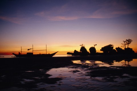 PHILIPPINES, Visayan Islands, Boracay Island, Boat and rocky outcrop silhouetted at sunset