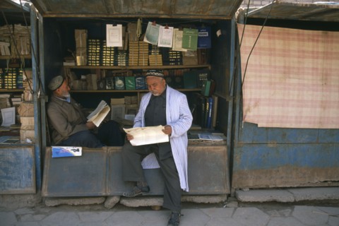 CHINA, Xinjiang , Kashgar, Muslim men reading at bookstall.