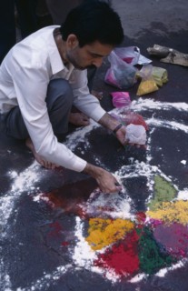 INDIA, Delhi , Painting patterns on ground as base for bonfire during Hindu Holi Festival.