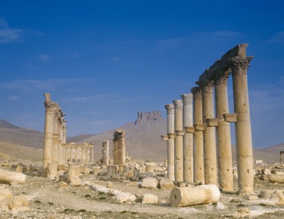 SYRIA, Central, Tadmur, "Monumental Arch, columns and fallen masonry with fort on hillside beyond.