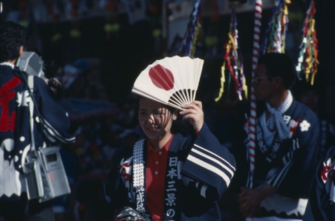 JAPAN, Honshu, Miyajima, Woman at the autumn Sake Festival holding a fan with the design of the