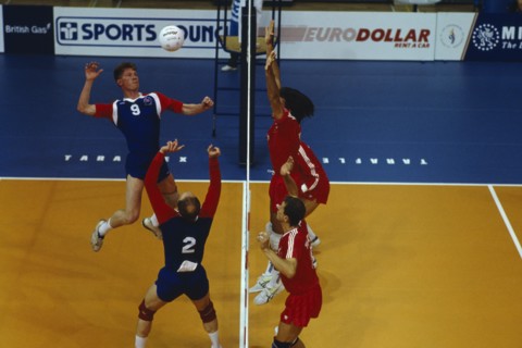 10066168 SPORT  Ball Games Volleyball Indoor volleyball match with players at net leaping for ball.