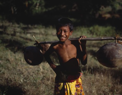 INDONESIA, Lombok, Timur, Mawon near Kuta a young boy in floral sarong holding pole of dried