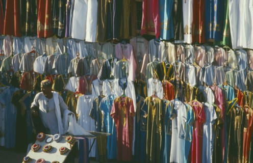 EGYPT, Luxor, Clothes stall in market with male vendor standing infront of racks hung with