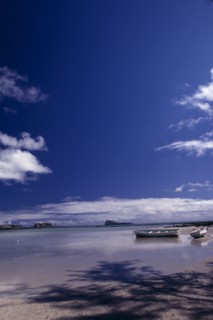 MAURITIUS,  , Grande Gaube, Sandy Beach with moored Boats and an Island in the distance with blue