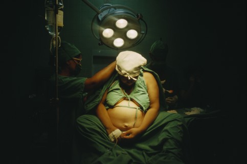 CUBA, Havana, Woman in labour sitting on an operating table with doctors at her sides