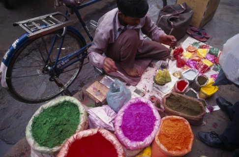INDIA, Delhi, Man with brightly coloured powdered paints for use during the Holi Festival.