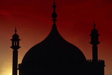 ENGLAND, East Sussex, Brighton, The Royal Pavilion. Detail of domes silhouetted at sunset with a