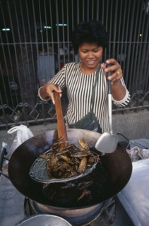 THAILAND, Bangkok, Woman cooking insects in a wok at a market stall
