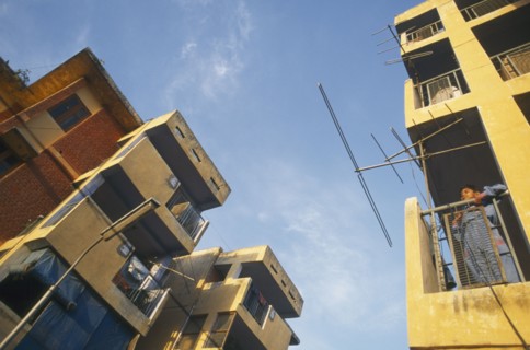 INDIA, Uttar Pradesh , Delhi, New housing estate. View looking up at buildings with boy standing on