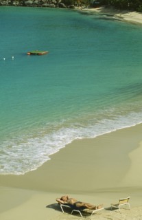 WEST INDIES, St.Martin, Grande Case Beach, Man sunbathing on sun lounger by the water’s edge